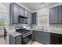 A modern kitchen featuring gray cabinets, stainless steel appliances, and granite countertops at 6045 Park Close, Fairburn, GA 30213