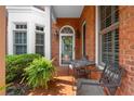 Inviting brick-paved front porch with seating, potted ferns, and view of the brick and bay window exterior at 8730 Parker Pl, Roswell, GA 30076