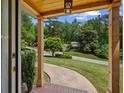 Inviting covered front porch view, framed by wooden beams, with a glimpse of the serene, tree-lined street and the house in the distance at 3912 Edenton Ne Ct, Brookhaven, GA 30319