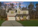 Charming two-story home featuring white siding, brick accents, covered porch, and an attached two-car garage at 205 Carrington Pt, Canton, GA 30115