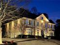 Two-story brick home illuminated at night, featuring a balcony, manicured shrubs, and an attached garage at 198 Grandmar Chase, Canton, GA 30115