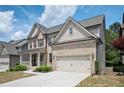 Charming two-story brick house with a covered front porch and an attached two-car garage on a sunny day at 2927 Dolostone Way, Dacula, GA 30019