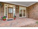 Welcoming front porch featuring a stylish wooden door, brick flooring, and decorative flower pots at 9395 Clublands Dr, Alpharetta, GA 30022