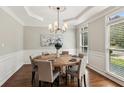 Bright dining room with a wooden table and six chairs, featuring wainscoting, tray ceilings, and large windows at 4140 Lansfaire Ter, Suwanee, GA 30024