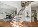 Elegant foyer showcasing a staircase with decorative metal spindles, hardwood floors, and access to adjacent rooms at 4140 Lansfaire Ter, Suwanee, GA 30024