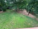Lush backyard featuring mature trees, verdant lawn, and a charming storage shed at 6542 Cherry Tree Ln, Atlanta, GA 30328
