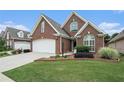 Charming brick home with an attached two-car garage, complemented by a lush green lawn and manicured landscaping at 2050 Woodberry Run Dr, Snellville, GA 30078