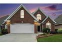 Beautiful brick home with a well-manicured lawn and a two-car garage, offering classic curb appeal at sunset at 2050 Woodberry Run Dr, Snellville, GA 30078