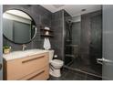 Modern bathroom with sleek, dark tiled walls, glass enclosed shower, round mirror, and contemporary vanity at 480 John Wesley Dobbs Ne Ave # 418, Atlanta, GA 30312