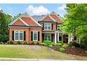 Charming red brick home boasts a manicured lawn, mature trees, and classic architectural details at 105 Thorncliff Way, Acworth, GA 30101