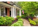 Inviting front porch with classic columns, lush landscaping, and American flag at 105 Thorncliff Way, Acworth, GA 30101