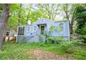 Inviting blue cottage-style home with a flag, mature trees, and a walkway leading to the front door at 1941 Headland Dr, East Point, GA 30344