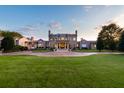 View of the grand home exterior with a circular driveway and manicured lawn at sunset at 1040 W Conway Nw Dr, Atlanta, GA 30327