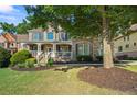 Beautiful brick home with a covered front porch and mature tree, offering shade and curb appeal at 4731 Moon Chase Dr, Buford, GA 30519
