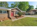 Brick home with a red door and landscaping, showcasing classic curb appeal at 6459 Paula Ct, Rex, GA 30273