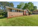 Quaint brick house with a red door and lush green lawn in a residential neighborhood at 6459 Paula Ct, Rex, GA 30273