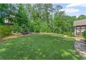 Expansive backyard with lush green lawn, mature trees, and landscaped garden beds at 11155 Highfield Chase Dr, Johns Creek, GA 30097