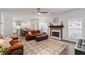 Open-concept living room with a fireplace, ceiling fan, and a view into the eat-in kitchen at 2580 Glaramara Ter, Cumming, GA 30041