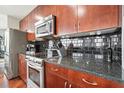 Cherry wood kitchen features stainless steel appliances, granite countertops, and stylish black backsplash at 400 W Peachtree Nw St # 3801, Atlanta, GA 30308
