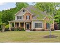 Inviting two-story home with stone accents, a cozy front porch, and lush green lawn at 7505 Antique Barn Ave, Cumming, GA 30041