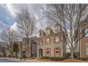Two-story gray brick home featuring red shutters, black fencing and mature trees lining the street at 319 Barbados Ln, Suwanee, GA 30024