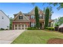 Traditional brick home showcasing manicured front lawn, professional landscaping, and a spacious three-car garage at 6250 Vista Crossing Way, Cumming, GA 30028