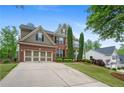 Traditional brick home showcasing manicured front lawn, professional landscaping, and a spacious three-car garage at 6250 Vista Crossing Way, Cumming, GA 30028