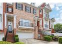 Brick townhome featuring an attached garage, upper balcony, and manicured shrubbery at 1215 Comet View Se Trl, Smyrna, GA 30082