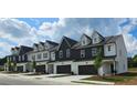 New construction townhomes featuring a two-car garage and dormer windows with modern white and dark siding at 208 Sharon Ln, Loganville, GA 30052