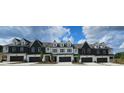 New construction townhomes featuring a two-car garage and dormer windows with modern white and dark siding at 208 Sharon Ln, Loganville, GA 30052