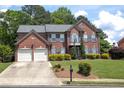 Beautiful brick home featuring a manicured lawn, mature trees, and classic shuttered windows at 601 Hexham Ct, Suwanee, GA 30024