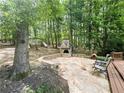 A stone backyard patio featuring an outdoor fireplace and comfortable seating, surrounded by lush greenery and trees at 1045 River Pt, Suwanee, GA 30024