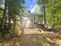 A spacious backyard features a stone patio with outdoor seating, a wooden deck, and ample greenery at 1045 River Pt, Suwanee, GA 30024