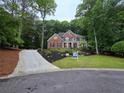 Inviting brick home nestled among trees, with professional landscaping, and a curved driveway at 1045 River Pt, Suwanee, GA 30024