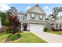 Two-story home with gray siding, two-car garage, manicured lawn, and vibrant foliage at 129 Prominence Ct, Canton, GA 30114