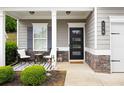 Inviting front porch with seating, modern door, stone accents, and manicured landscaping at 129 Prominence Ct, Canton, GA 30114