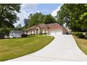 Spacious home featuring a two-car garage and an expansive driveway, surrounded by lush greenery at 427 Picketts Lake Dr, Acworth, GA 30101
