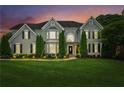 An elegant two-story home at dusk featuring a manicured lawn and traditional architectural details at 110 Keswick Way, Alpharetta, GA 30022