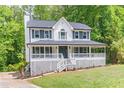 Beautiful two-story home with a covered porch, shutters, and lush greenery at 5139 Coolamber Dr, Powder Springs, GA 30127