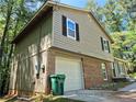 Exterior shot of a two-story home with siding, brick, an attached garage, and lots of surrounding trees at 3832 Natalie Way, Ellenwood, GA 30294