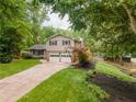 View of the two-story home showing the two-car garage and a nicely landscaped front yard with room to play at 287 West Wind Dr, Lilburn, GA 30047