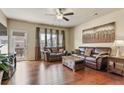 Cozy living room featuring gleaming hardwood floors, a ceiling fan, and comfortable leather seating at 4181 Integrity Way, Powder Springs, GA 30127