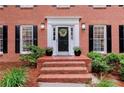 Close up of a classic white-trimmed door, brick steps, and decorative plants at 1582 E Bank Dr, Marietta, GA 30068