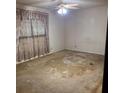 Spacious bedroom featuring worn carpet, a ceiling fan, and a window with floral curtains at 2368 Ebenezer Se Rd, Conyers, GA 30094