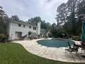 Expansive backyard featuring a covered pool, patio furniture, and a serene wooded backdrop at 3 Perthshire Dr, Peachtree City, GA 30269