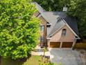 Stunning aerial view of a brick home with a two-car garage, mature trees, and a well-maintained roof at 5105 Tynewick Ne Trce, Roswell, GA 30075