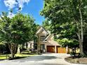 Beautiful home with a brick exterior, mature trees, a two-car garage, and a well-manicured lawn, set under a clear blue sky at 5105 Tynewick Ne Trce, Roswell, GA 30075