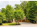 Traditional brick home with lush trees, manicured lawn, and a two-car garage, offering curb appeal at 5105 Tynewick Ne Trce, Roswell, GA 30075