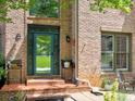Close-up of a brick home's entrance with decorative door, porch seating, and manicured landscaping details at 5105 Tynewick Ne Trce, Roswell, GA 30075