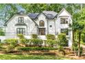 Gorgeous white home featuring a manicured lawn, mature landscaping and unique wrought iron fencing detail at 900 Edgewater Nw Dr, Atlanta, GA 30328